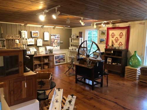 A cozy museum room featuring wooden floors, various artifacts, artwork, and display cases.