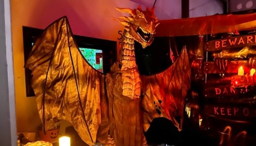A large, golden dragon figure with wings spread, set against a dark, spooky backdrop with warning signs.