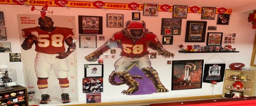A wall decorated with Kansas City Chiefs memorabilia, featuring player posters, framed photos, and team-themed decor.