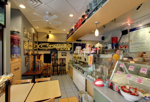 A cozy ice cream shop interior with colorful decor, a display case, and seating areas.