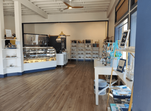 A bright, modern shop interior with display cases, shelves of products, and wooden flooring.
