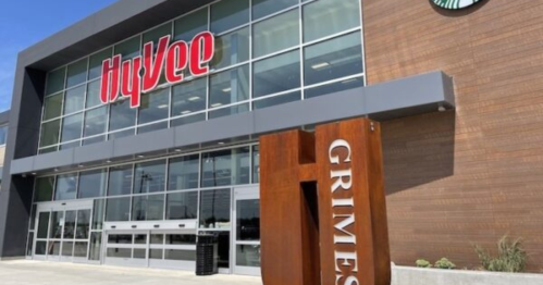 Exterior of a Hy-Vee grocery store in Grimes, featuring large windows and a prominent sign.