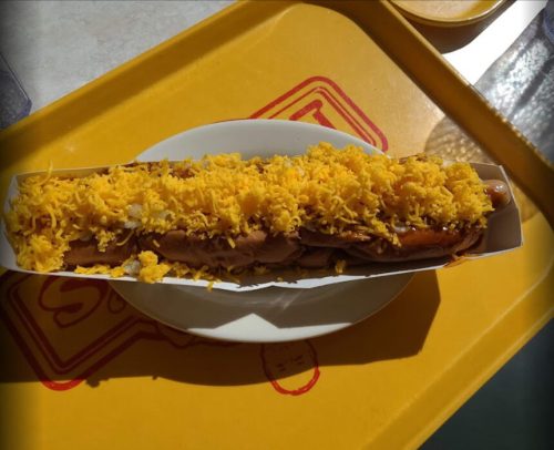 A long dish filled with rice and topped with yellow saffron, served on a white plate on a yellow tray.