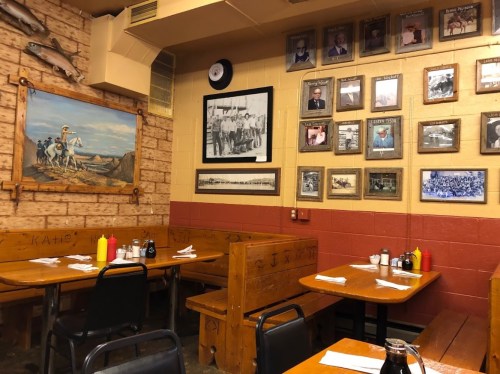 Cozy restaurant interior with wooden tables, condiment bottles, and framed historical photos on the walls.