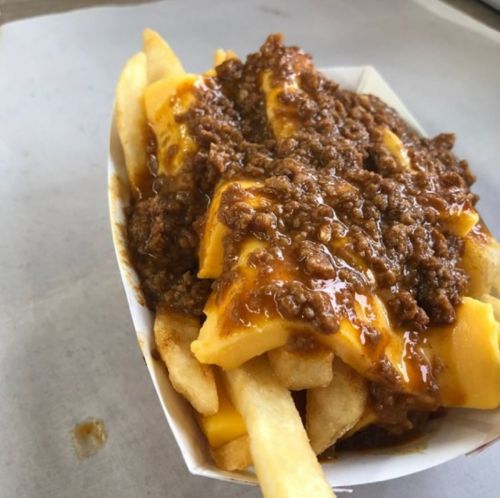 A serving of fries topped with melted cheese and a hearty chili sauce.