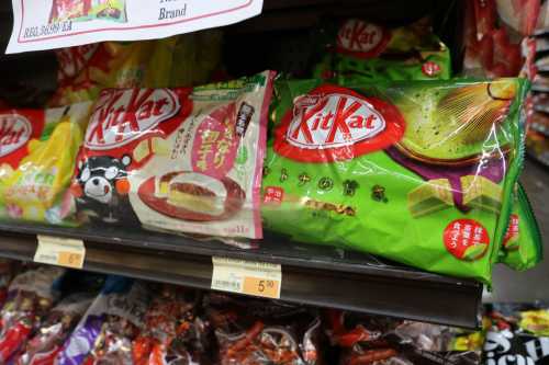 Two varieties of KitKat bars on a store shelf, one with a chocolate flavor and the other with a green tea flavor.