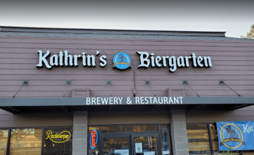 Sign for Kathrin's Biergarten, a brewery and restaurant, featuring a blue logo and "Open" sign in the window.
