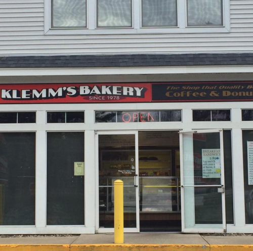 Front view of Klemm's Bakery, featuring a sign that says "OPEN" and showcasing a variety of baked goods inside.