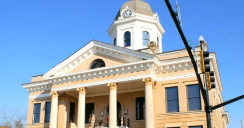 Historic building with a clock tower, featuring columns and a clear blue sky in the background.