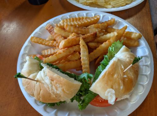 A plate with two sandwiches filled with lettuce and tomato, accompanied by a side of crinkle-cut fries.
