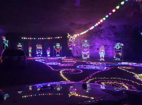 Colorful light display featuring animated characters in a cave, with vibrant patterns and decorations on the ground.