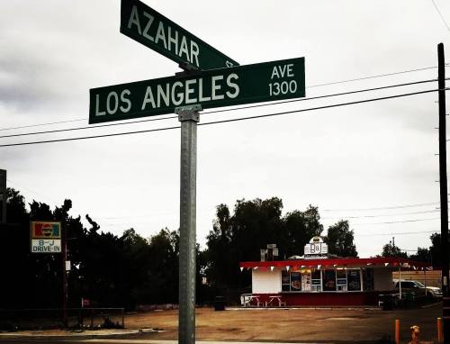 Street sign at the intersection of Azahar and Los Angeles Ave, with a drive-in restaurant in the background.