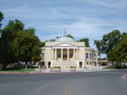 A large, round building with a dome and columns, surrounded by trees and a clear blue sky.
