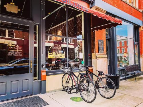 Bicycles parked outside a storefront with large windows and a red awning in a historic downtown area.