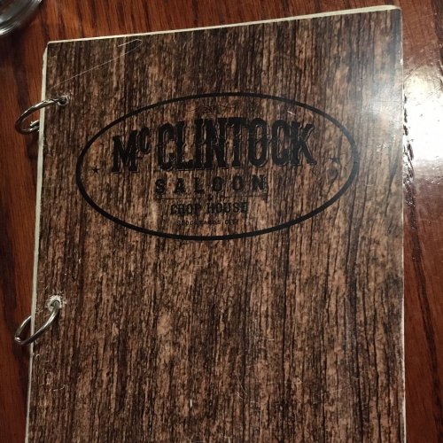 Menu cover for McClintock Saloon, featuring a wood grain design and circular logo.