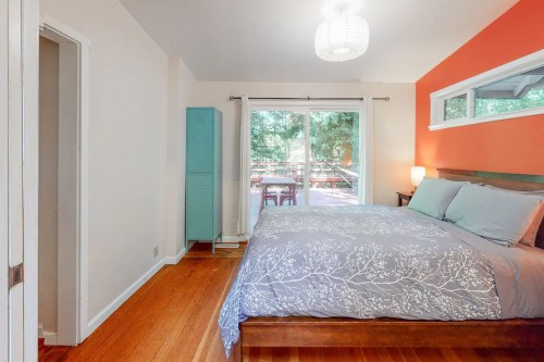 Cozy bedroom with a large bed, light blue accents, and a view of a deck through sliding glass doors.