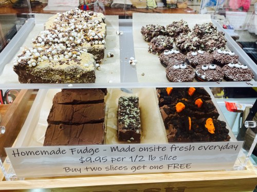 Display of homemade fudge slices, including chocolate and nut varieties, with a sign promoting a buy-two-get-one-free offer.