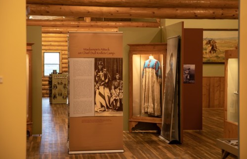 Interior of a museum exhibit featuring historical displays, including banners and traditional clothing.