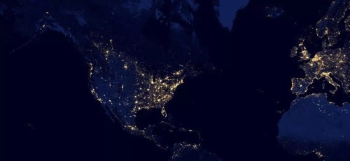 A satellite image of North America and Europe at night, showcasing city lights and geographical features.