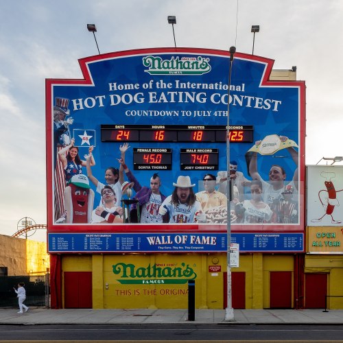 A large billboard for Nathan's Hot Dog Eating Contest, showing a countdown to July 4th and featuring past champions.