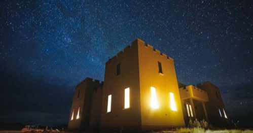 A castle-like structure illuminated at night under a starry sky.