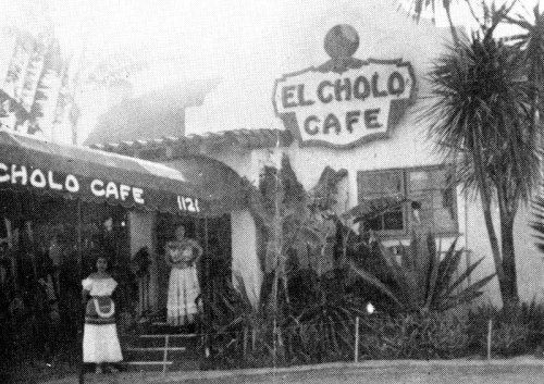 Historic black-and-white photo of El Cholo Cafe, featuring a woman in traditional attire outside the entrance.