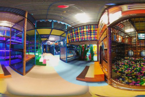 A colorful indoor play area with climbing structures, ball pits, and vibrant lighting.