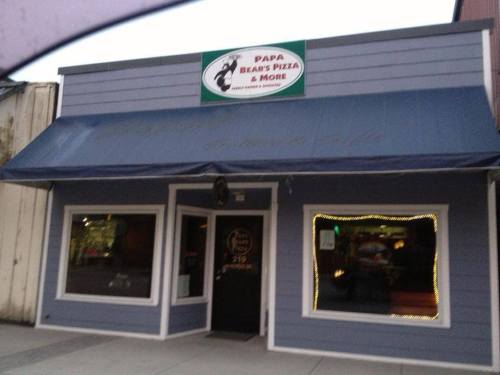Exterior of Papa Bear's Pizza & More, featuring a blue building with a sign and awning, and illuminated windows.