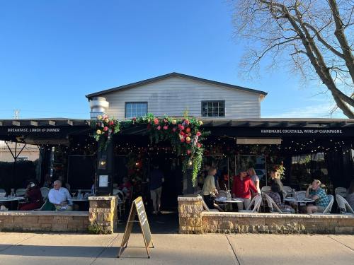 A bustling outdoor dining area with patrons enjoying meals under floral decorations and a clear blue sky.