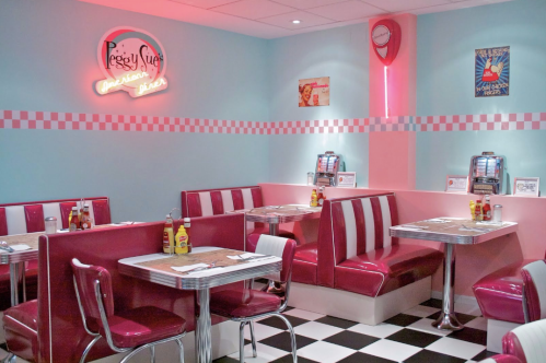 A retro diner interior with pink booths, checkered floor, neon sign, and vintage jukeboxes.