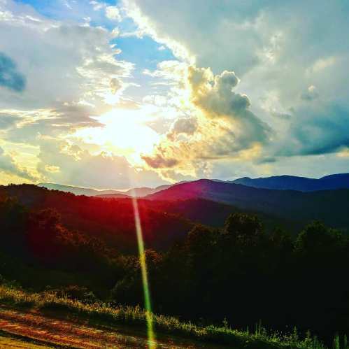 A vibrant sunset over rolling hills, with colorful clouds and a serene landscape.