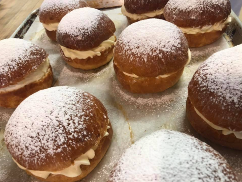 A tray of fluffy cream-filled pastries dusted with powdered sugar.
