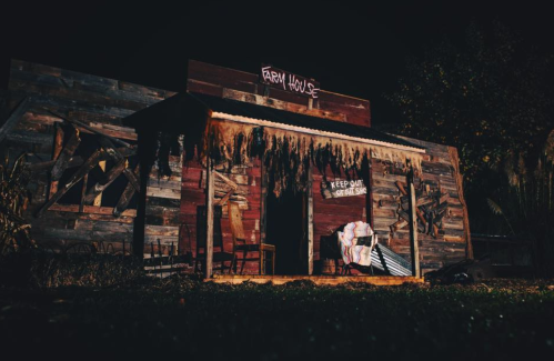 A spooky, abandoned farmhouse at night, with a "Keep Out" sign and eerie decorations.
