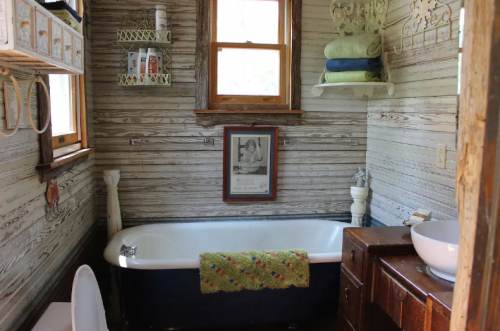 A cozy bathroom featuring a vintage clawfoot tub, wooden accents, and neatly arranged towels and toiletries.