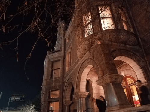 A historic stone building illuminated at night, with intricate architectural details and a dark sky above.