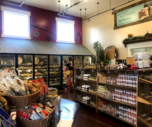 Interior of a cozy store featuring shelves of products, a display of baked goods, and large glass refrigerators.