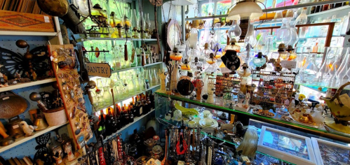 A vibrant antique shop filled with various collectibles, glassware, and decorative items on shelves and displays.