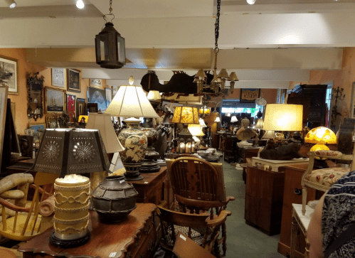 A cozy antique shop filled with various lamps, furniture, and vintage decor items.