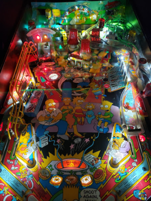 A colorful pinball machine featuring characters from "The Simpsons," with bright lights and dynamic artwork.