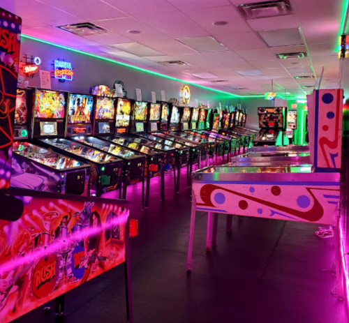 A vibrant arcade filled with pinball machines and neon lights, creating a lively gaming atmosphere.