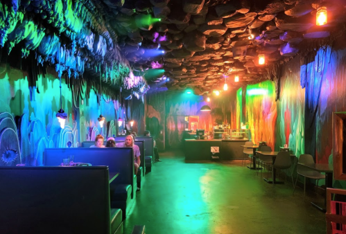 A vibrant, colorful lounge with a textured ceiling, glowing lights, and cozy seating areas.