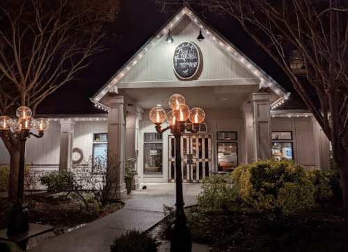 A charming restaurant exterior at night, adorned with string lights and a decorative lamp post.