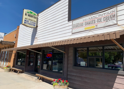 Exterior of Hi-Mountain restaurant with signs for burgers, shakes, and ice cream, featuring an "Open" neon sign.