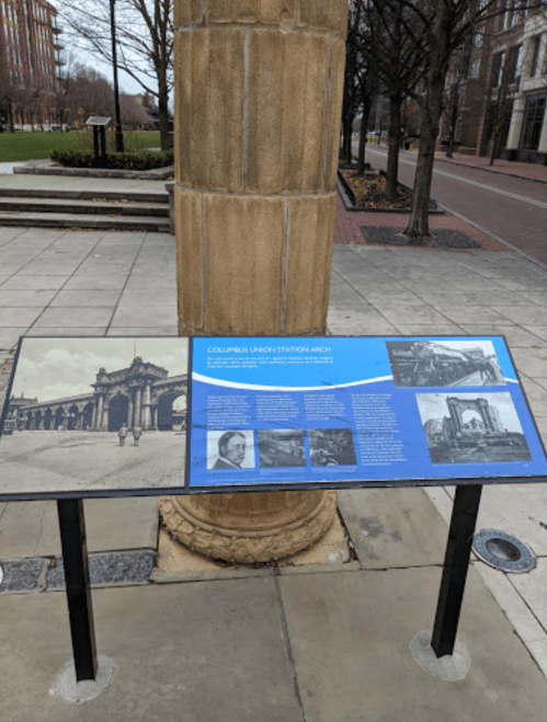 Historical display about Columbus Union Station, featuring images and text on a blue panel in a park setting.