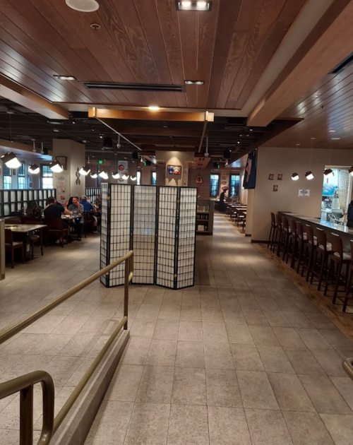 Interior of a restaurant featuring wooden decor, tables, and a folding screen separating sections.