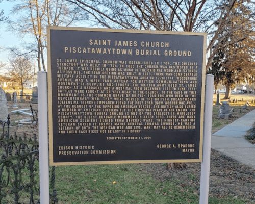 Sign detailing the history of Saint James Church and Piscatawaytown Burial Ground, with information on its establishment and significance.