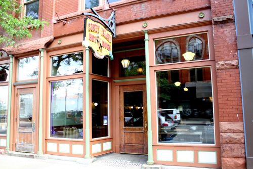 Exterior of a brick building featuring large windows and a vintage sign that reads "Silly Goose Restaurant."