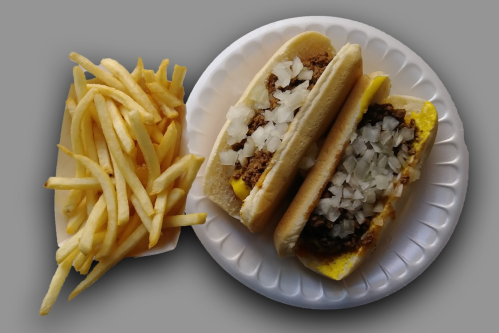 Two hot dogs topped with chopped onions on a paper plate, accompanied by a serving of golden French fries.