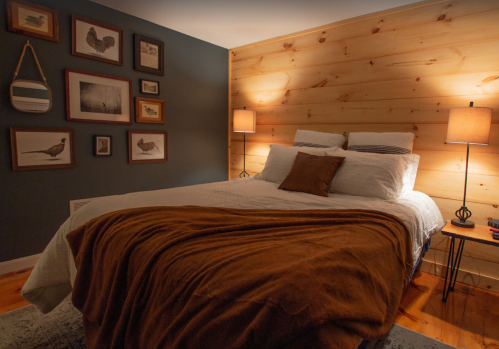 Cozy bedroom with a wooden accent wall, framed art, and warm lighting from bedside lamps.