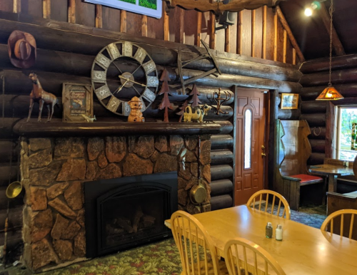 Cozy log cabin interior featuring a stone fireplace, wooden decor, and rustic furnishings.